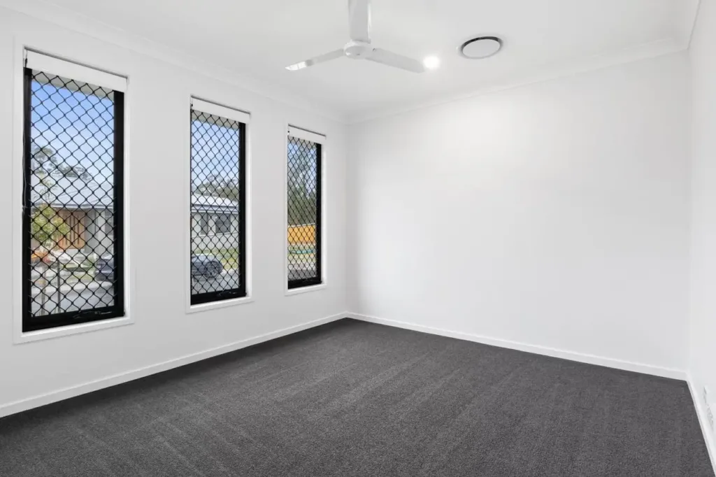 thompson-building-co-modern-granny-flat-interior-construction Newly constructed modern granny flat interior with carpeted flooring, black window frames, and ceiling fan.
